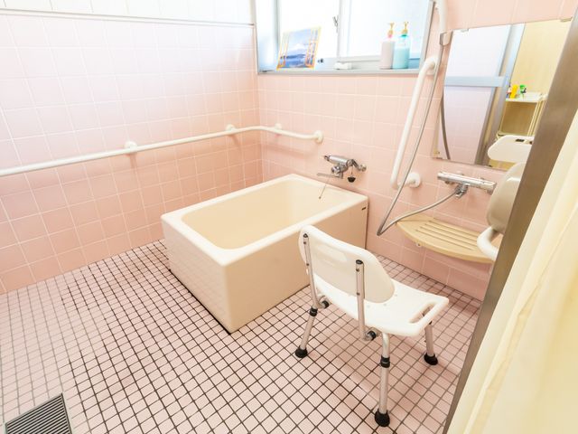 ピンクのタイルの浴室 浴室 手すり付きの安全な浴室で、ご利用者の快適な入浴をサポートします。清潔感あふれる空間を大切にしています。