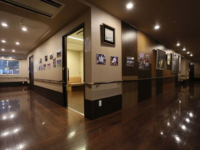 廊下に飾られた写真と絵 廊下 ゆったりとした廊下は、壁に飾られた絵や写真で温かみを感じさせる空間です。手すりが整備され、安全に配慮された設計になっています。