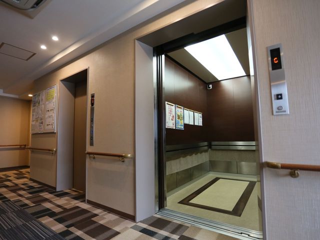 広々としたエレベーター室内 エレベーター 手すり付きで安全性を考慮したエレベーターです。広くて明るい廊下と調和しており、どなたでも使いやすい設計になっています。