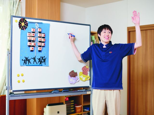 人々が活動する室内 多目的室 多目的室で掲示物を説明しています。清潔で明るい空間が魅力的です。