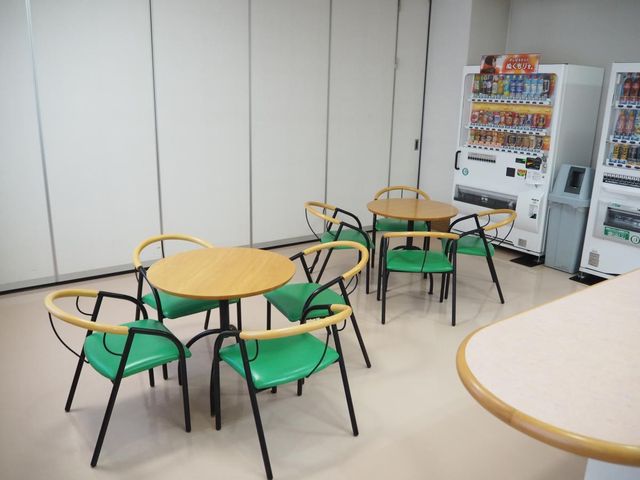 自販機とテーブルの休憩室 休憩室 明るい空間に配置されたテーブルと椅子です。休憩や会話を楽しめるスペースが確保されています。