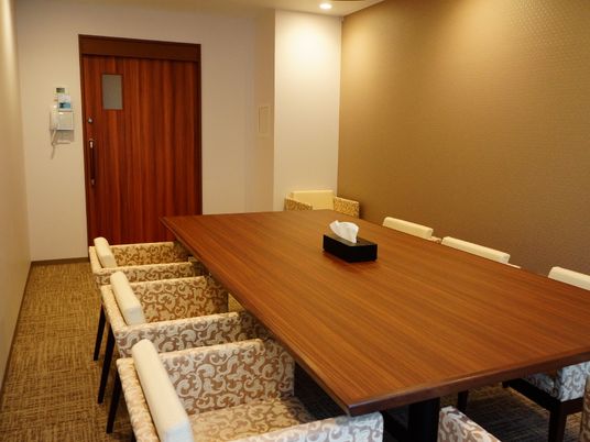 応接室はベージュとブラウンを基調としたインテリアである。大きな長方形の木製テーブルに椅子が6脚セットされている。