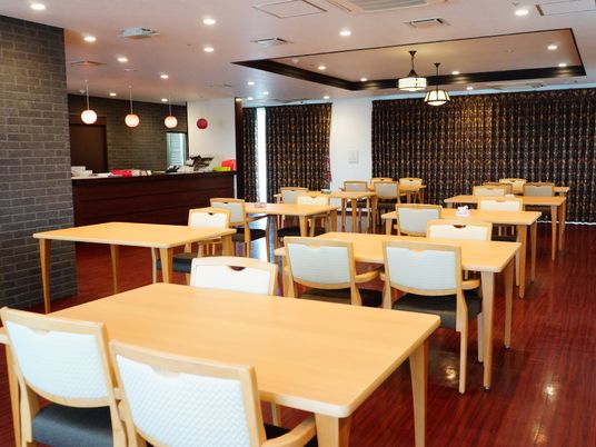 レストランの中には明るいブラウンの木製テーブルが並んでいる。天板は長方形で、椅子が向かい合わせにセットされている。