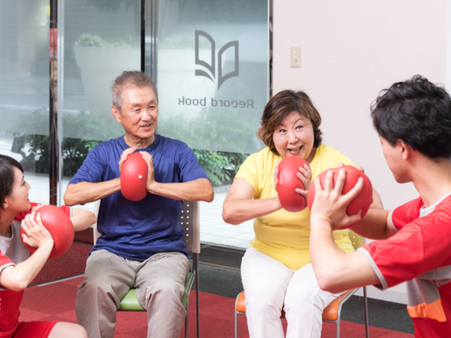 運動器具を使ったトレーニング室 機能訓練室 赤いボールを使い、楽しそうに運動をしています。チームでの活動で、コミュニケーションも深まります。