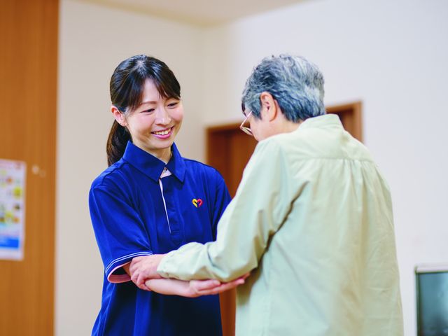 親切なスタッフと利用者 スタッフイメージ 笑顔のスタッフが温かく利用者をサポートする、安心感のある場面です。就業環境が和やかです。