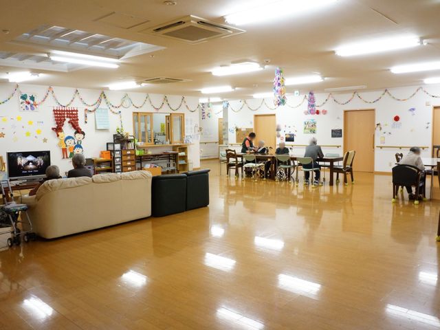 多機能空間の日常風景 共有スペース 飾り付けが施された広々とした部屋で、利用者の方々が日々の活動を行っている様子が見受けられます。共有空間としての温かさが伝わる設計です。