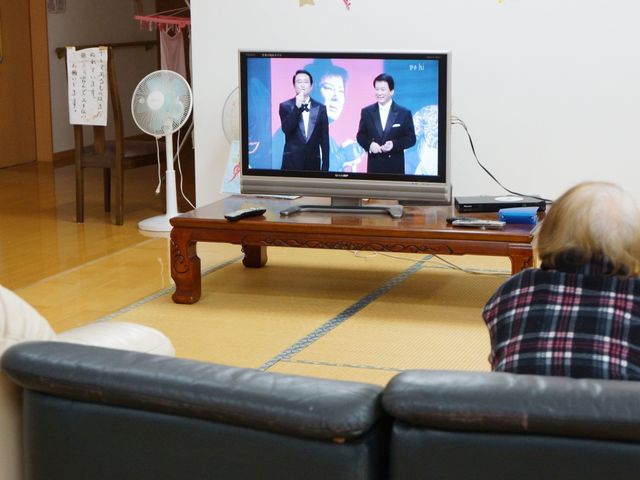 和室でテレビ鑑賞 共有スペース ゆったりとした和室で、住人がテレビを楽しんでいます。共有スペースでの憩いのひとときを提供しています。