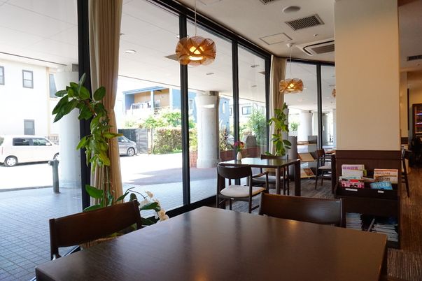 日差しの指す、椅子とテーブル、絵画が設置された共有スペース