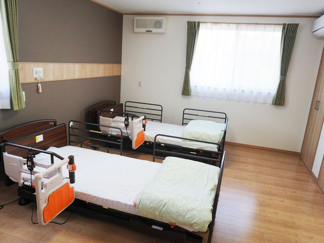 清潔な二人部屋居室 柔らかな光が差し込む快適な居室です。安全に配慮されたベッドが二台設置され、共に生活する方との安心を支えます。