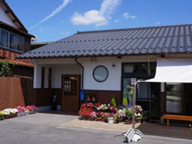 花が彩る施設の外観 外観 青空の下にある、色とりどりの花で囲まれた建物のエントランスです。明るく快適な職場環境が整っています。