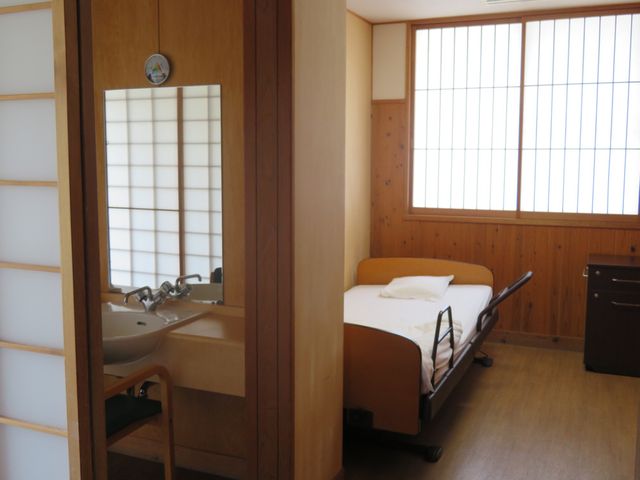 清潔な個室居室 居室 落ち着いた色合いの個室は、快適な生活空間を提供します。柔らかな光が入る窓や、実用的な洗面台が整っております。