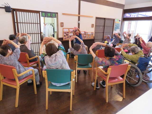 多世代の様子和室 体操 明るく広々とした和の空間で、様々な世代の方々が体操に励んでいます。和やかな雰囲気の中、健康維持に役立つ日常の一コマです。