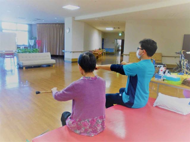 機能訓練の様子 機能訓練室 明るく広々とした空間で、専門のスタッフが丁寧に体操指導を行っています。様々な器具を使用し、日々の生活に必要な体力や機能の向上をサポート致します。