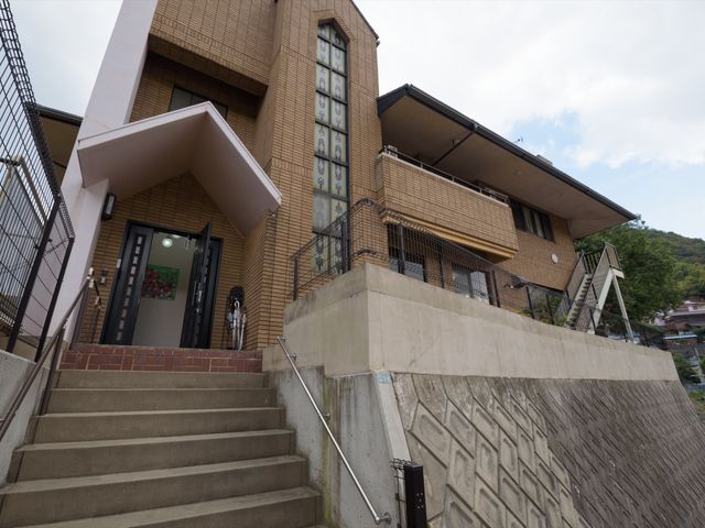 エントランスと階段のある建物 外観 ゆるやかな階段を備えたエントランスは、来訪者を温かく迎えます。明るさと開放感が感じられる設計です。