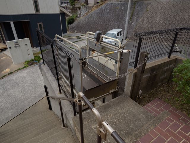 斜面に設置された階段リフト 外観 ゆるやかな坂道に沿って設置された階段リフトは、アクセシビリティの向上を図っています。安心してご自身のペースで移動できる、心強い設備です。