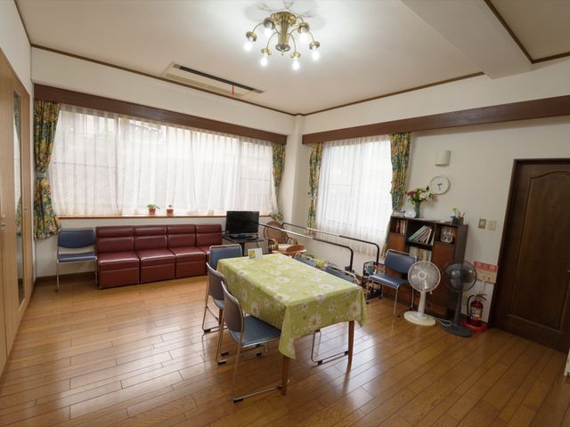 居心地の良い居室 共有スペース ゆったりとしたソファと温もりを感じさせる木の床が特徴の快適な居室です。明るい窓辺には、お花や小物も飾られており、安らぎの空間が広がっています。
