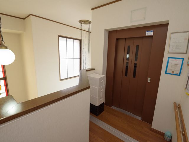 エレベーター付き玄関ホール エレベーター 手すりが設置された温かみのあるエントランスです。エレベーターも完備しており、全ての方が快適に移動できる設計になっています。