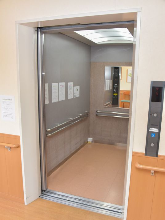 奥行きのあるエレベーター。手すりがエレベーター内部の各面に設置されており、安心して利用できる。奥には鏡がみえる。