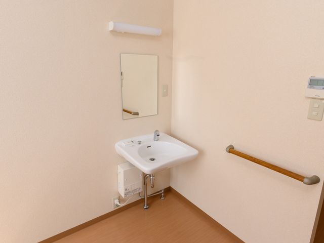明るい洗面所の一角 洗面台 手すりが備え付けられた機能的な洗面スペースです。日々の身支度に必要な快適さを考慮して設計されています。