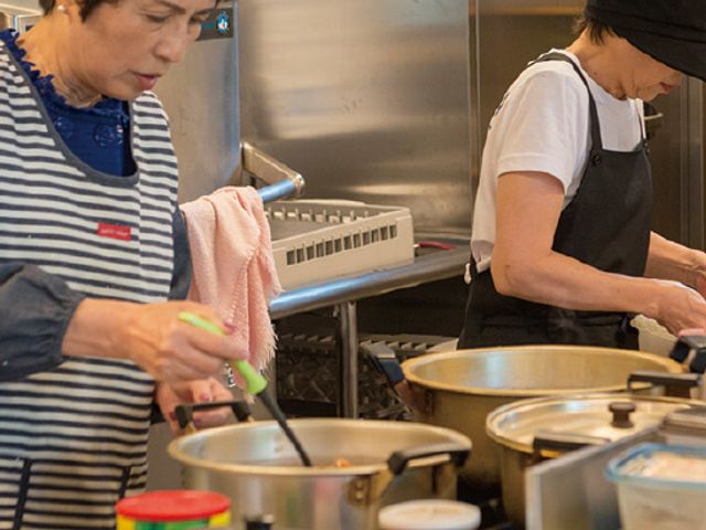 調理が行われているキッチン キッチン 広々とした調理スペースで、スタッフが丁寧に料理を準備しています。アイデアを活かした献立作りが可能です。
