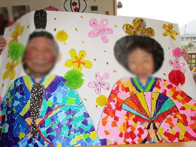 楽しげな表情の二人 ラウンジ 明るい空間で、利用者が手作りの作品を楽しそうに持っています。施設で楽しい時間を過ごせそうです。