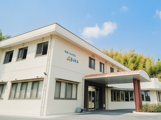 外観の建物正面 外観   青空の下に建つ2階建ての建物です。落ち着いた色合いで、入口には屋根付きのアプローチがあります。