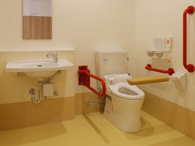 手すり付きのトイレ トイレ 手すりが設置されたトイレは、安全性を重視しています。バリアフリー設計で安心して利用できます。