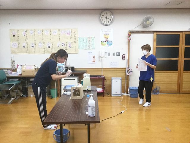 スタッフが作業する多目的室 多目的室   広い多目的室でスタッフが準備作業をしています。床に余裕があり、研修や活動の場として使いやすそうです。