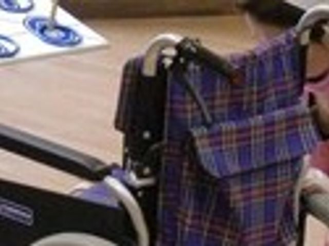 車椅子と利用者の様子 機能訓練室 車椅子が使用される場面のあるトレーニングエリアです。職員と一緒に活動が行われています。