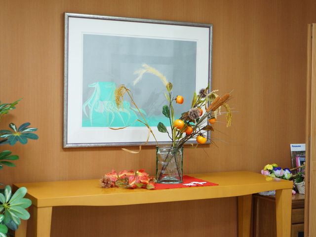 装飾されたロビーの一角 壁際 落ち着いた色合いのインテリアに季節の花が飾られ、暖かみのあるお迎えができるスペースです。