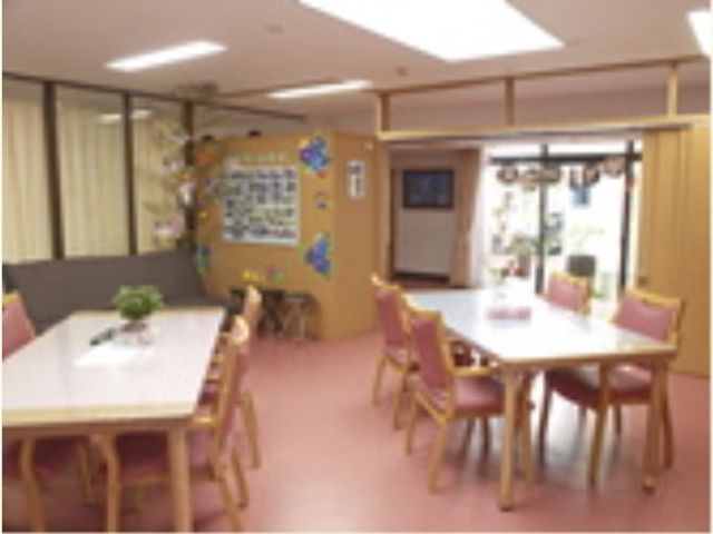 明るい食堂の様子 デイサービスルーム 広々とした食堂には、暖かみのある照明が心地よい雰囲気を演出しています。天気の良い日は、窓からの自然光がさらに明るさを加えます。