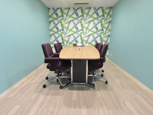 青と緑の模様が入った壁と水色単色の壁に囲まれた部屋には、舟形の会議用テーブルと6脚の椅子が置かれている。内装と紫色の椅子が個性的である。