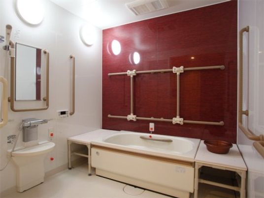 浴槽の横側１面の壁に茶系を取り入れた浴室である。自立の方が、お一人でも安心して入浴が行えるように所々に手すりを設置している。