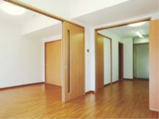 施設の写真 居室はフローリングである。壁は白色で統一されている。広々としていて、スライドドアで部屋を仕切ることができる。