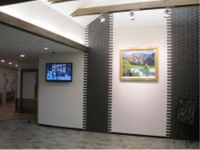 廊下に掲示物とテレビ 玄関 清潔感のあふれる廊下には情報を発信するモニターが設置され、壁面のアートが訪れる人の目を楽しませています。