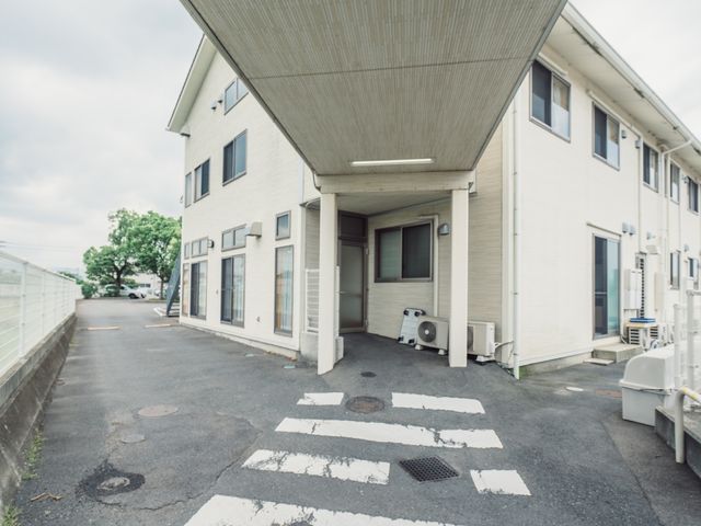 白い建物のエントランス 外観 広々としたエントランスでは安全な通行が確保されており、通勤時の快適さが支えられます。