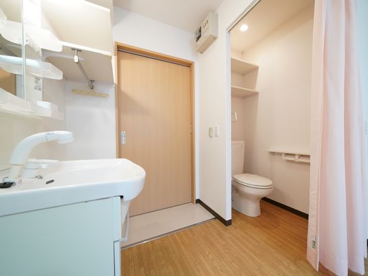 居室の入口入ってすぐの所に洗面台がある。その反対側には、カーテンで仕切られた空間にトイレがある。バリアフリー構造である。