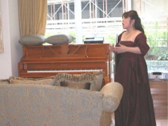 ピアノの前に立つ女性 コンサート 明るい窓辺で、心地よいピアノの音色に包まれるリラックスできる空間です。音楽を通じて、入居者の方々との交流も図れるでしょう。