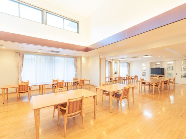 広々とした明るい食堂 食堂兼機能訓練スペース 天井が高くて開放感のある食堂です。機能的な配置のテーブルと椅子で、快適なお食事のひと時を提供します。