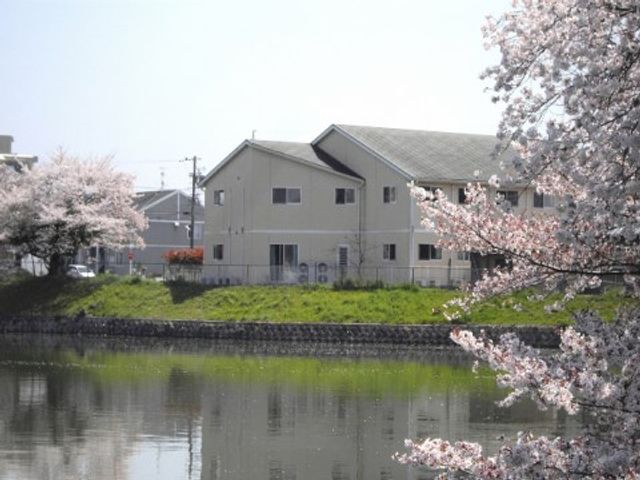 桜並木と建物の外観 外観 桜の木が彩る清々しい景観を楽しめる施設外観です。平穏な環境でのびのびとお過ごしいただけます。