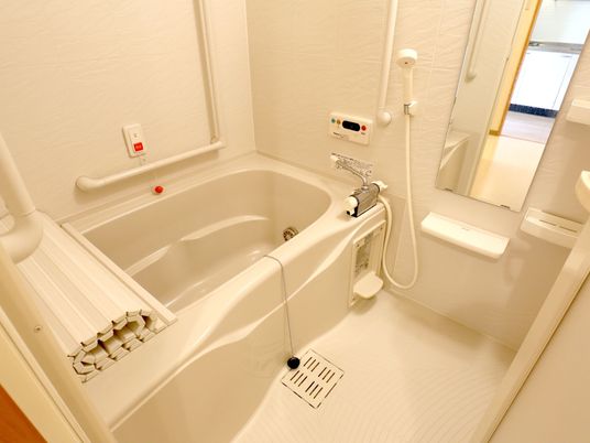 足を伸ばして入れる、ゆったりとした浴槽が置かれた浴室がある。洗い場や浴槽の近くには手すりが設置されている。