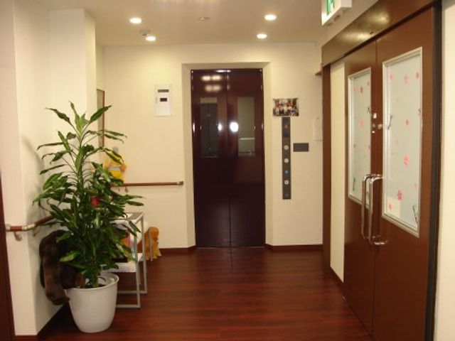 清潔感ある廊下と扉 エレベーターホール きれいに整頓された廊下が広がっており、ゆったりと歩くことができる空間です。周囲の掲示物も明るい印象を与えます。