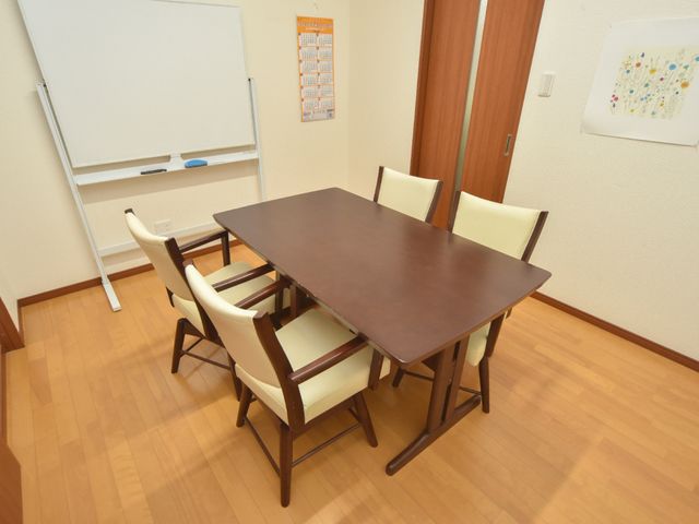 会議用テーブルと椅子の部屋 机と椅子のある部屋 ゆったりとした空間で、明るい窓際のテーブルが配置され、コミュニケーションを取りながらリラックスできる場所です。白板があり、研修などにも利用可能です。
