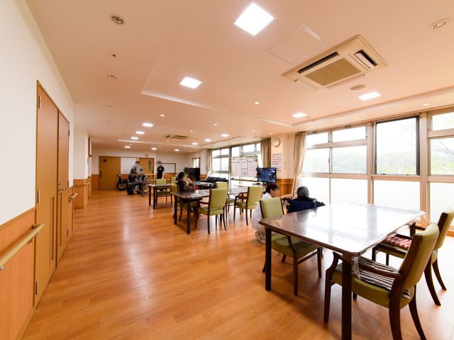 広々としたダイニングスペース リビング 明るく広々としたダイニングルームで、入居者が穏やかな時間を過ごしています。ゆとりある空間で、コミュニケーションもはかれそうです。