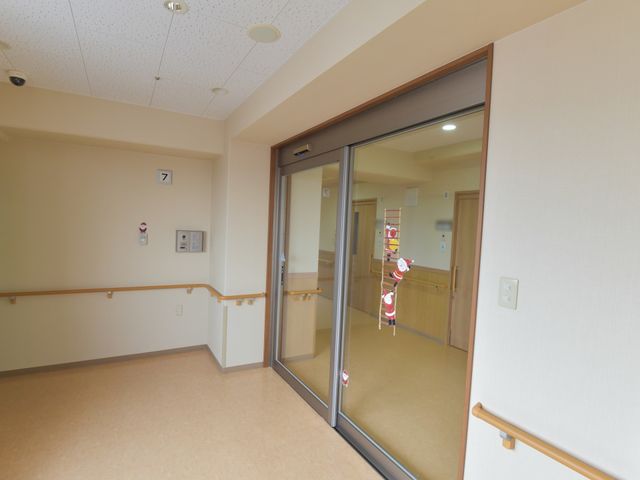 明るい廊下と自動ドア 7階 自動式のドアを完備した廊下がみなさまの動きをサポートし、ゆったりとした移動を可能にしています。安全に配慮された温かみのある設計が特長です。