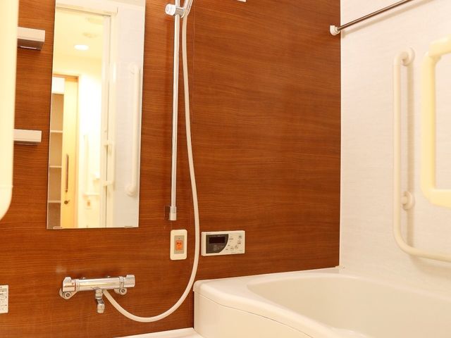 設備整った清潔な浴室 部屋の浴室 手すりやシャワーヘッドが調整可能な安全設計の洗い場です。ゆったりとしたバスタイムを支える環境が整っています。