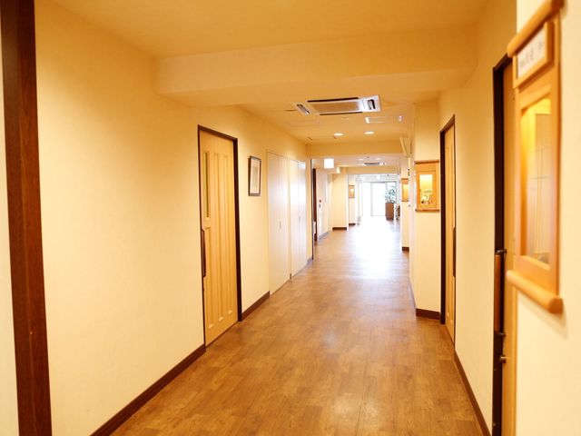 明るく広い施設の廊下 廊下 落ち着いた色合いの廊下は、広々としており歩きやすい造りです。ゆったりとした時間が流れる環境でお仕事をしませんか。