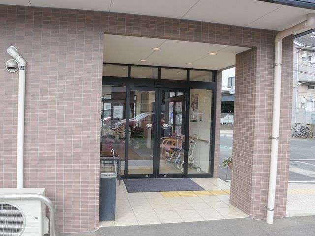 エントランスのガラス扉 玄関 ヒトのゆとりを感じられる歓迎のエントランスです。バリアフリー設計であることが見て取れ、車椅子の方でも安心して出入りできます。