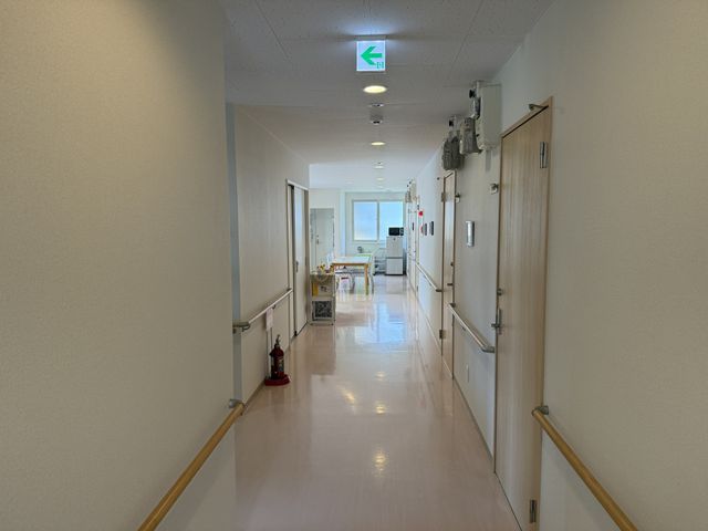 明るい廊下 廊下 手すりが設置された明るい廊下で、安全に移動できます。奥には広々としたスペースが広がっています。