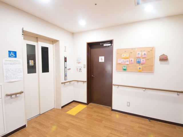 廊下と掲示物の様子 通路 手すりが設置された廊下は、安心して歩行できる設計です。壁面の掲示物からは、コミュニティの温かさが感じられます。